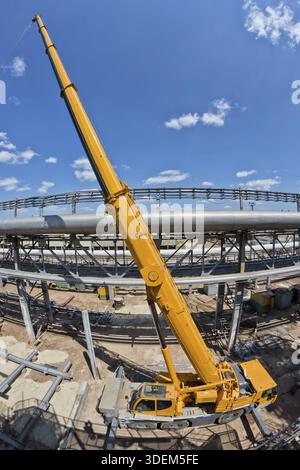 Vista dalla parte superiore dell'area di manutenzione su una grande gru da cento tonnellate con braccio esteso in piedi sul cantiere del nuovo settore petrolchimico Foto Stock