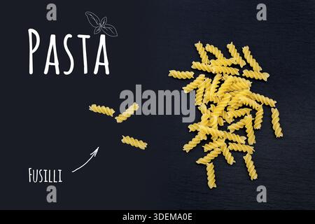 Non cotti pasta italiana Fusilli su ardesia nera pietra con sfondo bianco di scritte, vista dall'alto Foto Stock