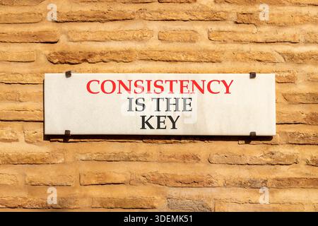La coerenza è il simbolo chiave. La coerenza delle parole concettuali è la chiave su una bellissima targhetta in marmo bianco. Bellissimo sfondo a muro in mattoni. Business co Foto Stock