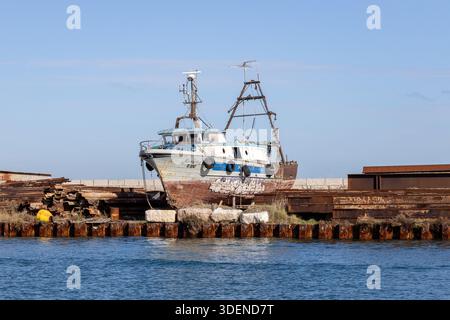Pellestrina, Venezia, Italia - 25 ottobre 2025: Vecchia barca da pesca che riposa in un cantiere navale lungo il lungomare della laguna veneta Foto Stock