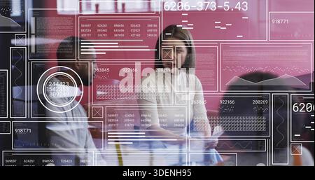 Con un tablet, una donna in una camicetta leggera che conduce una riunione di dati in ufficio attraverso una parete di vetro con HUD Foto Stock