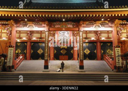Famoso punto di riferimento di Tokyo, il Tempio di Asakusa, colorato ingresso di notte con sagome di donna della preghiera e grande cane, Tokyo, Giappone Foto Stock