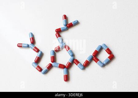 Pillole disposte formando una forma di DNA su un tavolo bianco, vista dall'alto piatto, concetto medico e scientifico che combina sanità, genetica e farmacia. Foto Stock