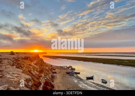 Tramonto sul molo e sulle vecchie barche da pesca in legno nella laguna di Naila, in Marocco Foto Stock