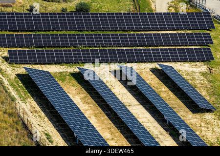 Vista aerea di una fattoria di energia rinnovabile con pannelli solari in un ambiente rurale, situata su un terreno grezzo Foto Stock