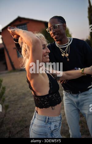 giovane coppia sorridente che balla fuori al tramonto Foto Stock