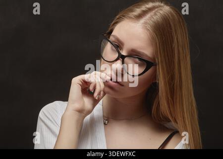 Ragazza triste e penosa che guarda la fotocamera su sfondo nero Foto Stock