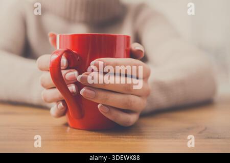 Primo piano di una donna con una tazza di bevanda calda Foto Stock