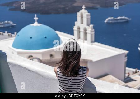 Donna di fronte alla Chiesa della Cupola Blu di Santorini, Grecia Foto Stock