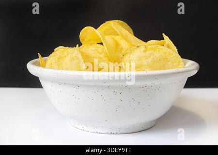 Spuntini croccanti di patate serviti in una ciotola bianca Foto Stock