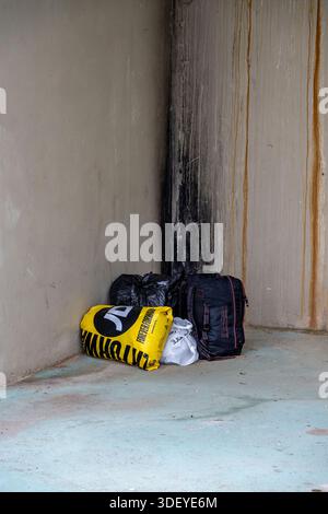 Senzatetto effetti personali in borse lasciate in un angolo tra due edifici per riparo in centro città. Foto Stock
