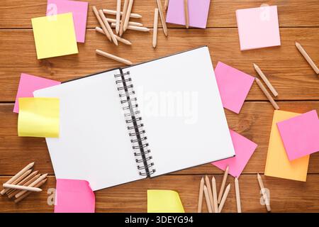 Spazio di lavoro creativo con notebook vuoto e note adesive colorate su un tavolo in legno Foto Stock