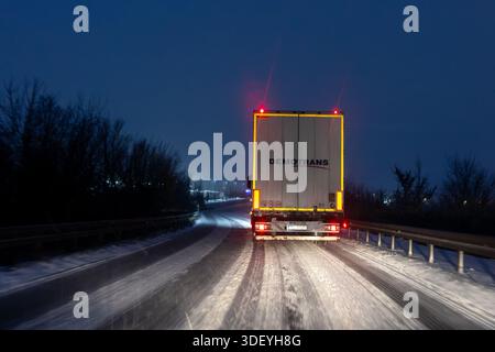 Magdeburgo, Germania. 9 gennaio 2026. Traffico di camion su strade innevate in Germania durante la tempesta di neve Elli. La scena notturna invernale mostra condizioni di guida difficili e una visibilità ridotta. Foto Stock