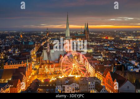 Chiesa di San Giacomo / Jakobikirche e ruota panoramica illuminata al mercatino di Natale serale in inverno a Koberg, città anseatica di Lübeck, Germania Foto Stock