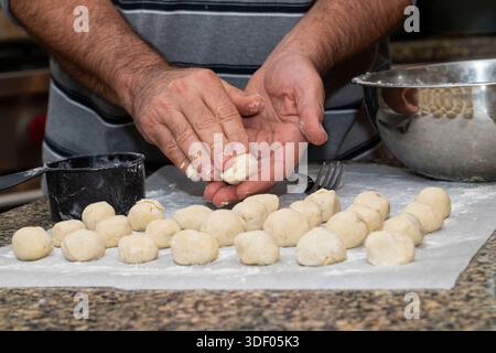 L'uomo tira fuori le palle di impasto Gnocchi fatto a mano Foto Stock