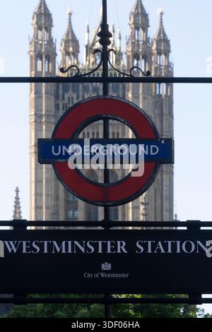 Stazione di Westminster, Londra. L'iconico cartello sotterraneo è incorniciato dalle Houses of Parliament, un simbolo della storia e del governo britannici. Foto Stock