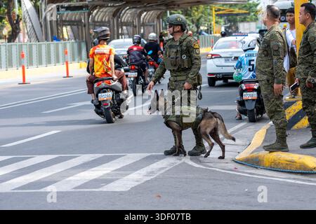 La polizia e il personale militare dispiegano un'unità K9 per gestire la folla e il traffico durante i preparativi per un grande festival religioso. Foto Stock