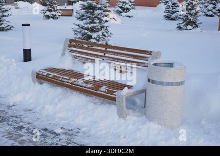 Panca in legno coperta di neve nel parco cittadino in inverno Foto Stock