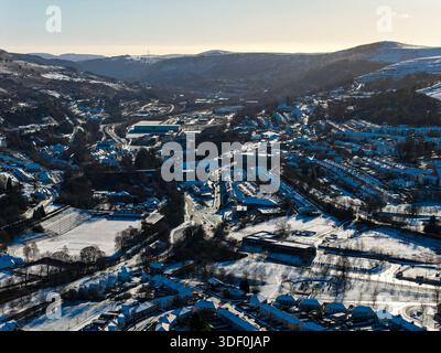La luce del sole invernale proietta lunghe ombre su una città innevata sulle colline gallesi Foto Stock