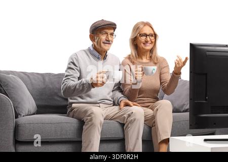 Allegra coppia matura che guarda la televisione e beve un caffè isolato su sfondo bianco Foto Stock