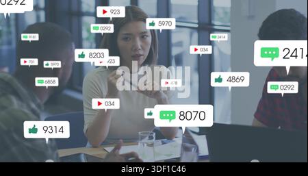 Donna di punta del centro che indossa la parte superiore leggera che tiene una penna che guida la riunione al tavolo con le sovrapposizioni per computer portatili Foto Stock