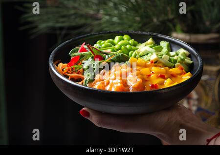 Deliziosa ciotola di salmone e avocado con semi di sesamo e alghe marine, fotografia gastronomica stilizzata, composizione di colori vivaci. Foto Stock
