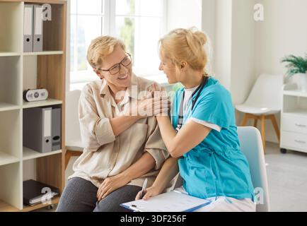 Infermiera sorridente che sostiene il paziente anziano durante la consultazione medica amichevole Foto Stock