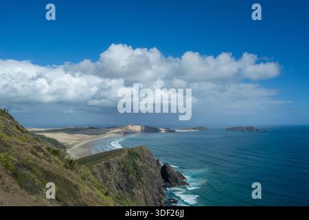 Uno splendido paesaggio costiero caratterizzato da scogliere, spiagge sabbiose e un cielo azzurro limpido con soffici nuvole. Le onde dell'oceano si infrangono dolcemente contro la costa, c Foto Stock