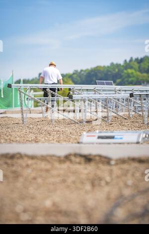Un lavoratore assembla strutture a pannelli solari su un tetto di ghiaia sotto un cielo blu, un nuovo parco e un garage per il parcheggio Calw Heumaden sul nuovo Hermann Hesseba Foto Stock
