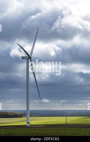 Turbina eolica in un campo verde sotto un cielo nuvoloso a Yrouerre, Francia Foto Stock