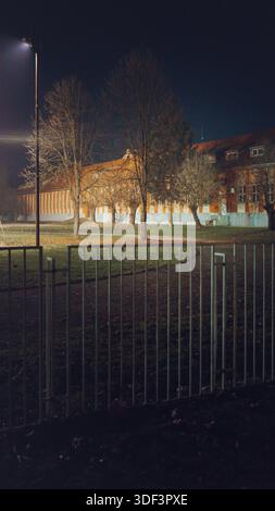 Scena notturna di un edificio scolastico recintato con cortile, stagione autunnale in Serbia, città di Cacak. Foto Stock