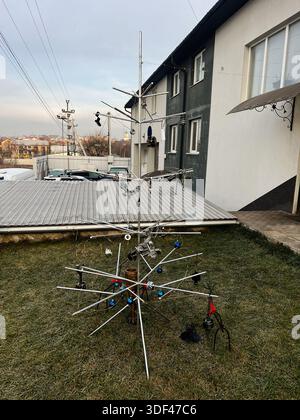 Scultura in metallo astratto all'aperto su un cortile erboso accanto a un edificio, con aste geometriche e ornamenti colorati. Foto Stock