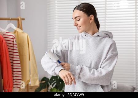 Donna che pulisce la felpa con rullo di lanugine a casa Foto Stock