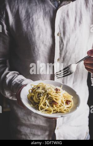 Piatto bianco con classica pasta di carbonara in mani maschili Foto Stock