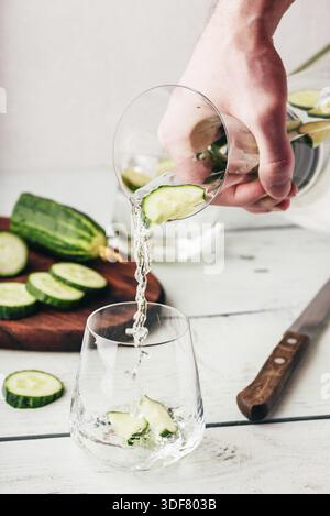 La caraffa versare l'acqua inumidita con cetriolo a fette Foto Stock