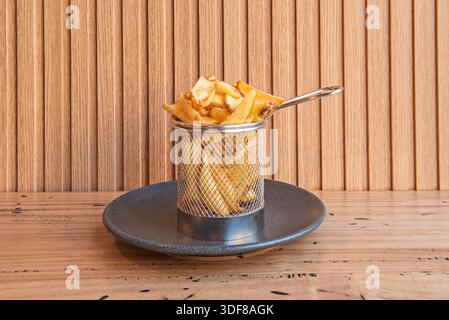 Servire con patatine lunghe e sottili, servite in un cestello di metallo argento, bollenti al vapore e con un tocco di sale marino friabile Foto Stock