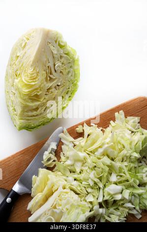 ​​cabbage tagliato finemente o cavolo Savoy su un tagliere di legno, accanto alla metà di un altro cavolo su sfondo bianco. Cibo sano e vegetariano Foto Stock