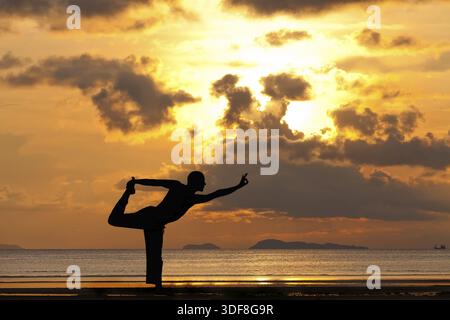 Silhouette uomo facendo esercizi yoga natarja a Sunset beach Foto Stock