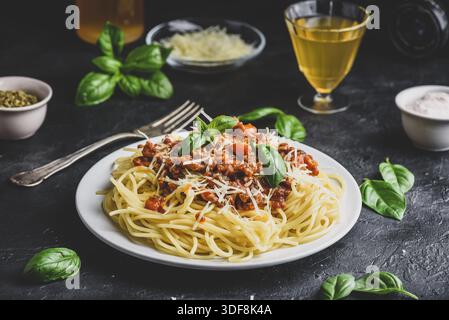 Spaghetti con salsa bolognese, parmigiano grattugiato e foglie di basilico fresco Foto Stock