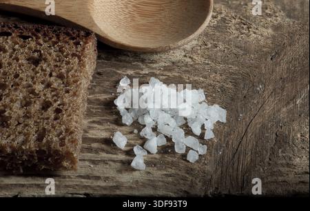Pane grezzo di segale con sale grossolano su un tavolo di legno, espresso macro Foto Stock