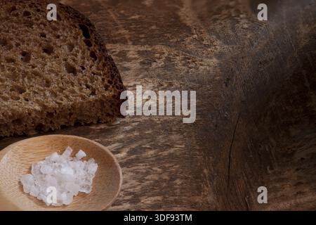 Tritare il pane grezzo di segale con sale grossolano su fondo di legno, espresso macro Foto Stock