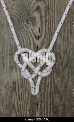 Nodo di corda marino sotto forma di fondo in legno a cuore, spazio di copia Foto Stock