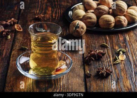 Il tè speziato con anice stellato, cardamomo e essiccato in calce armudu vetro sopra una superficie di legno Foto Stock