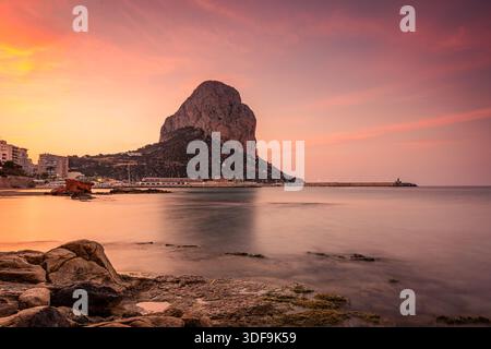 L'alba dorata dipinge il cielo sopra la roccia di Calpe mentre le calme acque del Mediterraneo si infrangono sulle rocce, Calpe, Spagna Foto Stock