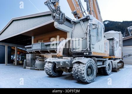 Vista panoramica escavatori idraulici congelati all'aperto condizioni invernali neve coperta ghiaccio industriale edificio alpino. Impatti a basse temperature Foto Stock