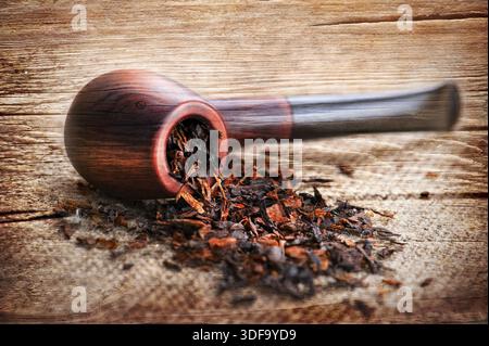 Trama in legno grunge con pipa da fumo e tabacco su tela di lino Foto Stock