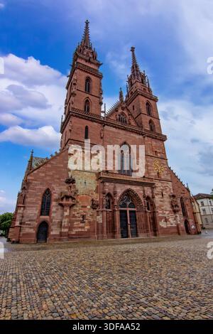Storica cattedrale gotica di Basilea con torri gemelle, facciata in pietra, piazza acciottolata e cielo spettacolare. Foto Stock