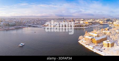 Una vasta veduta aerea panoramica catturata da un drone della vecchia città di Gamla Stan e dell'isola di Skeppsholmen coperte di neve durante una giornata invernale soleggiata a Stoccolma, Svezia. Foto Stock