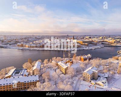 Una vista aerea con drone dell'isola di Skeppsholmen coperta di neve che guarda verso la storica città vecchia di Gamla Stan in inverno a Stoccolma, Svezia. Foto Stock