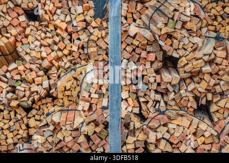 I fasci di legna da ardere per il riscaldamento rurale sono ben impilati e legati con corde nere, mostrando varie tonalità e texture di legno in una composizione verticale Foto Stock